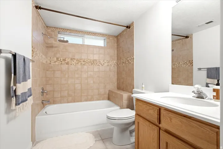 Bathroom featuring a tub/shower combination with tile surround and decorative mosaic accent