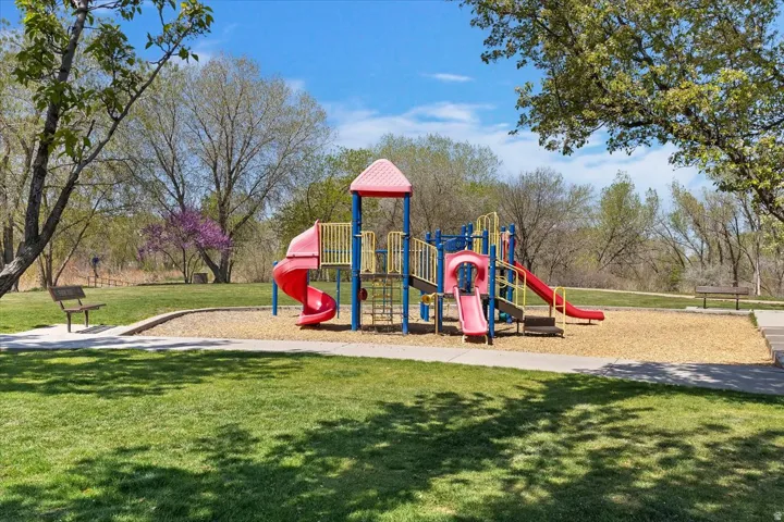 Expansive green space featuring a playground with multiple slides, a climbing structure, and wood chip surfacing