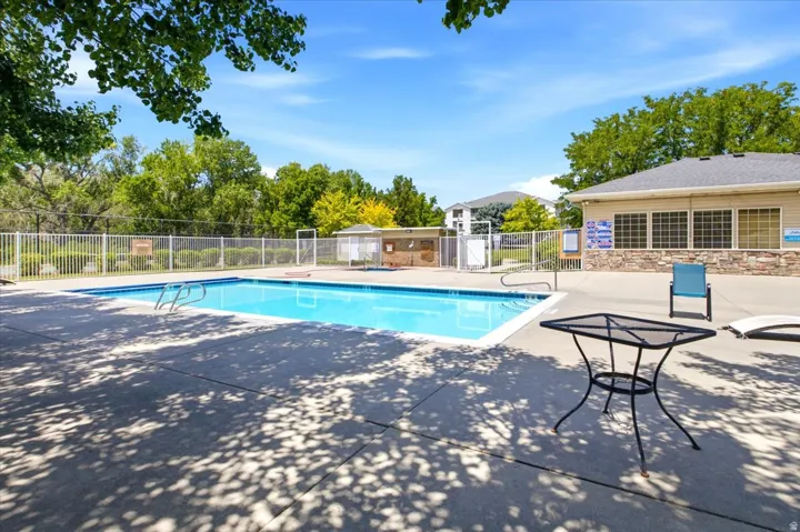 Community swimming pool with a concrete deck, surrounded by a white metal fence