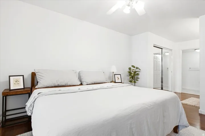Spacious bedroom featuring wood-finish flooring, a ceiling fan, and bright white walls
