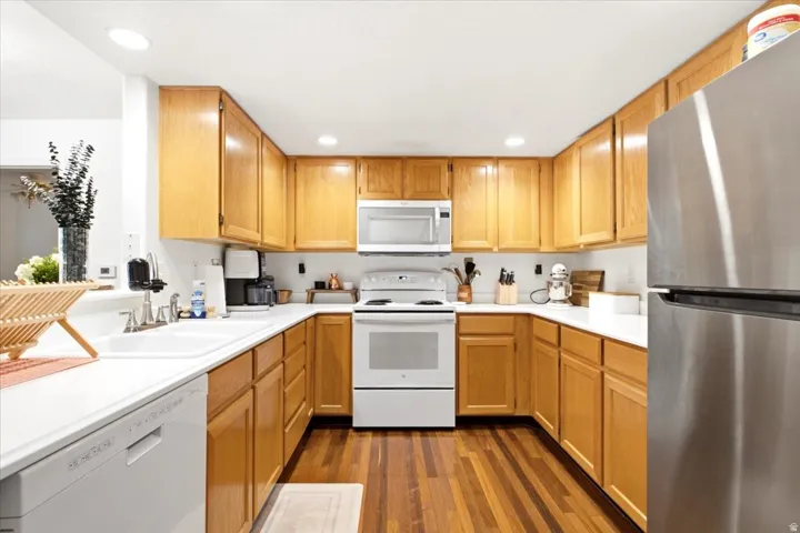 U-shaped kitchen with wood-finish flooring, light wood cabinetry, and white countertops