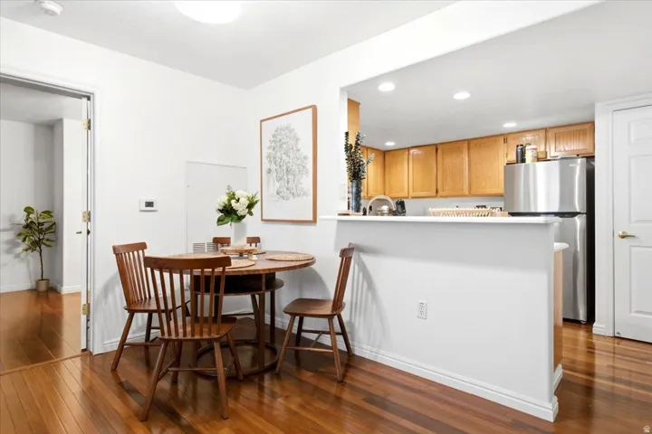 Open-concept dining area featuring wood-finish flooring, a pass-through counter, and recessed lighting
