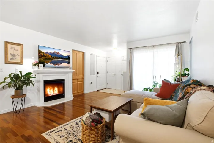 Living area featuring a white mantel fireplace, wood-finish flooring, and a large sliding glass door with sheer and opaque drapery