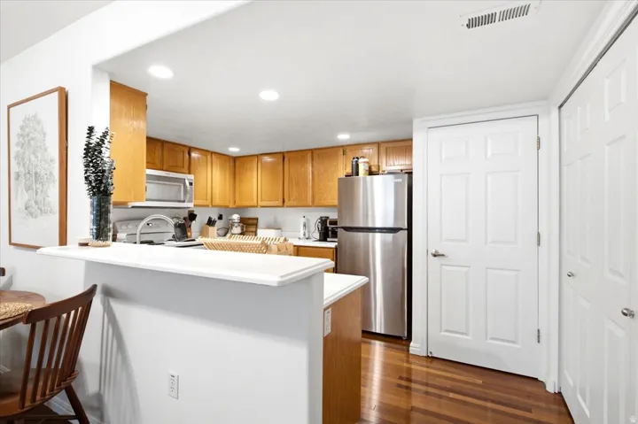 Kitchen featuring warm wood cabinetry, stainless steel appliances, a white countertop, recessed lighting, and wood-finish flooring