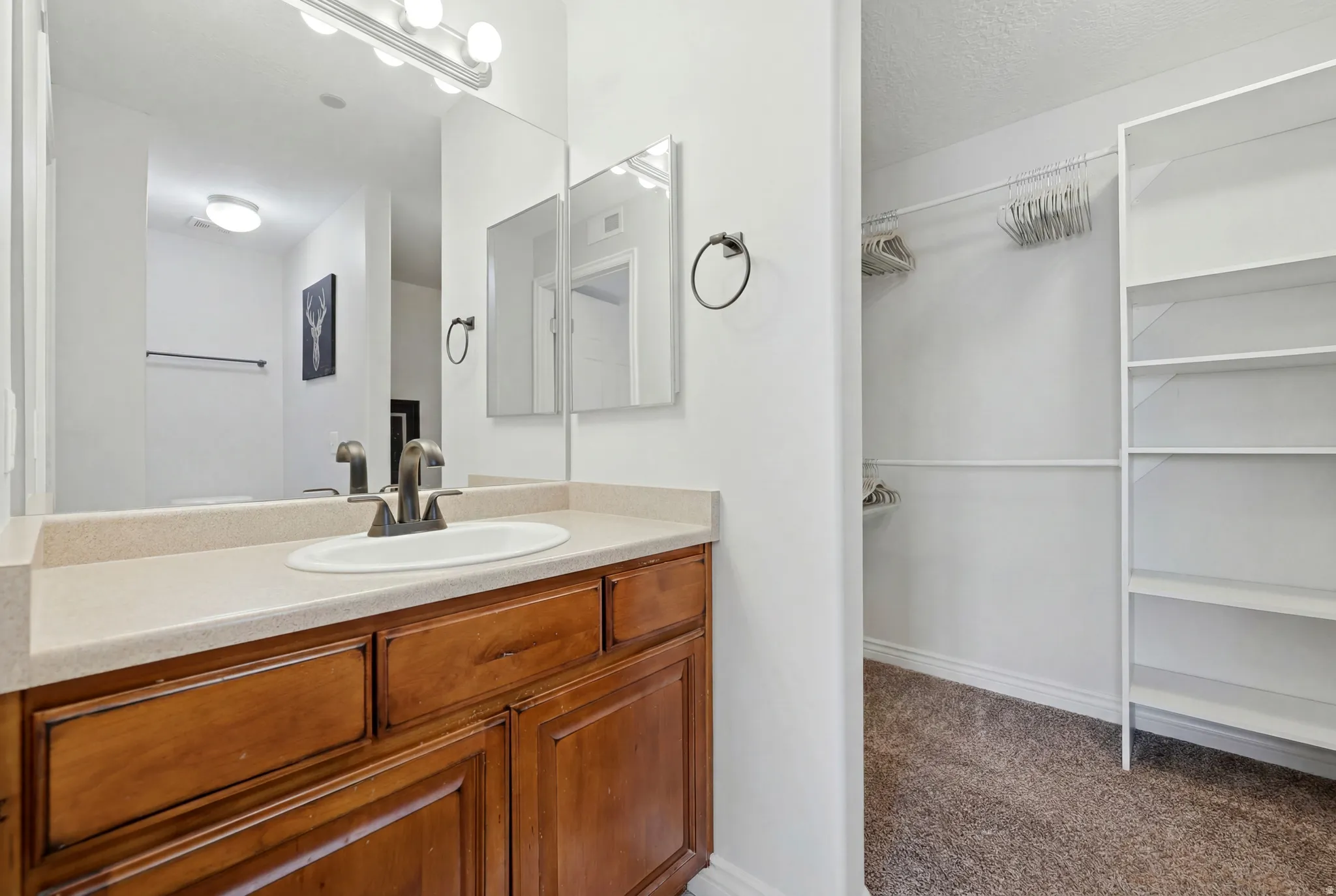 Vanity with a neutral countertop, undermount sink, and black-finish faucet