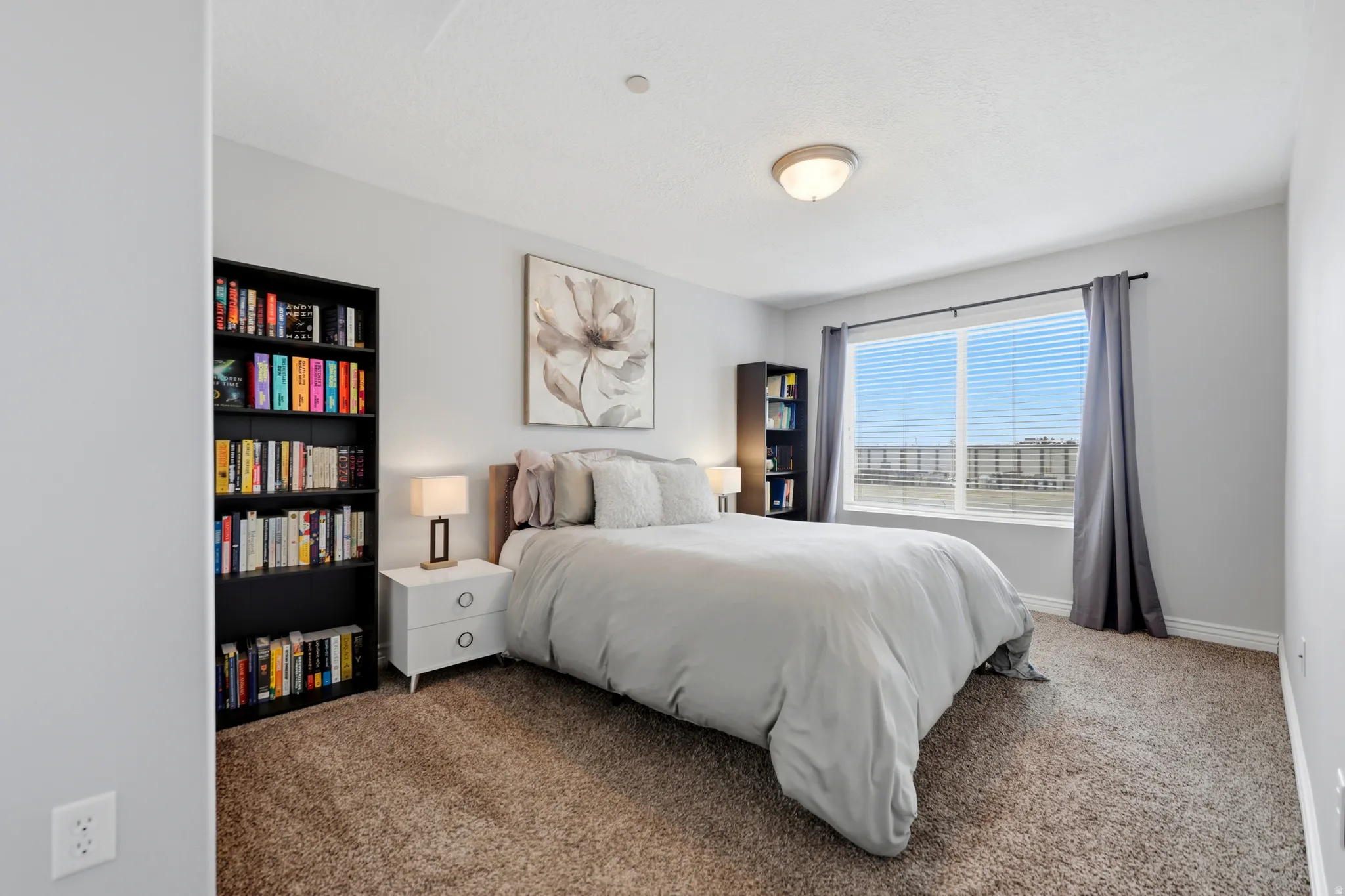 Carpeted room featuring a large window with horizontal blinds, light gray wall paint, a flush-mount ceiling light fixture, and white baseboards