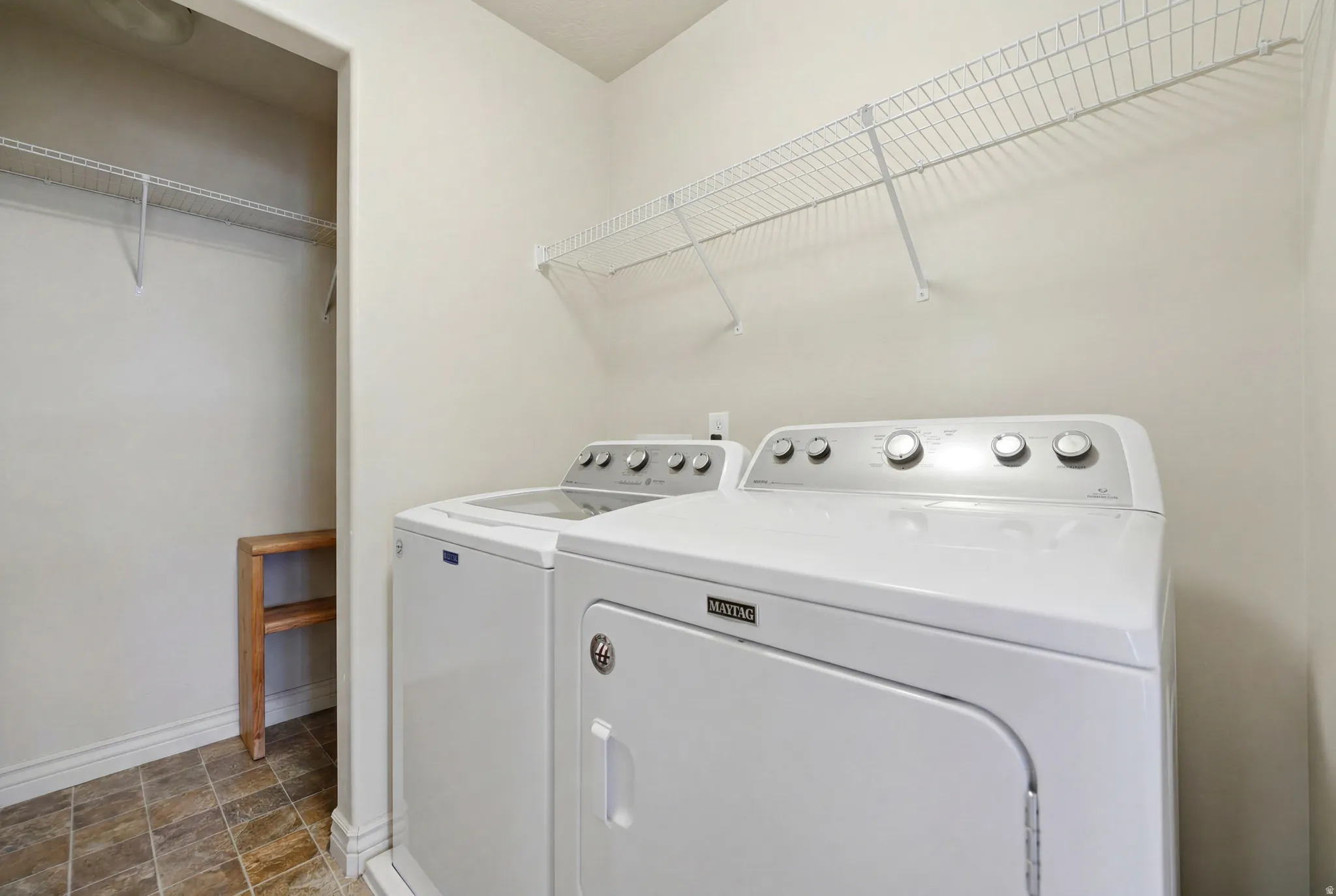 Dedicated laundry area featuring a washer and dryer, tile flooring, wire shelving, and an adjacent built-in wooden storage unit