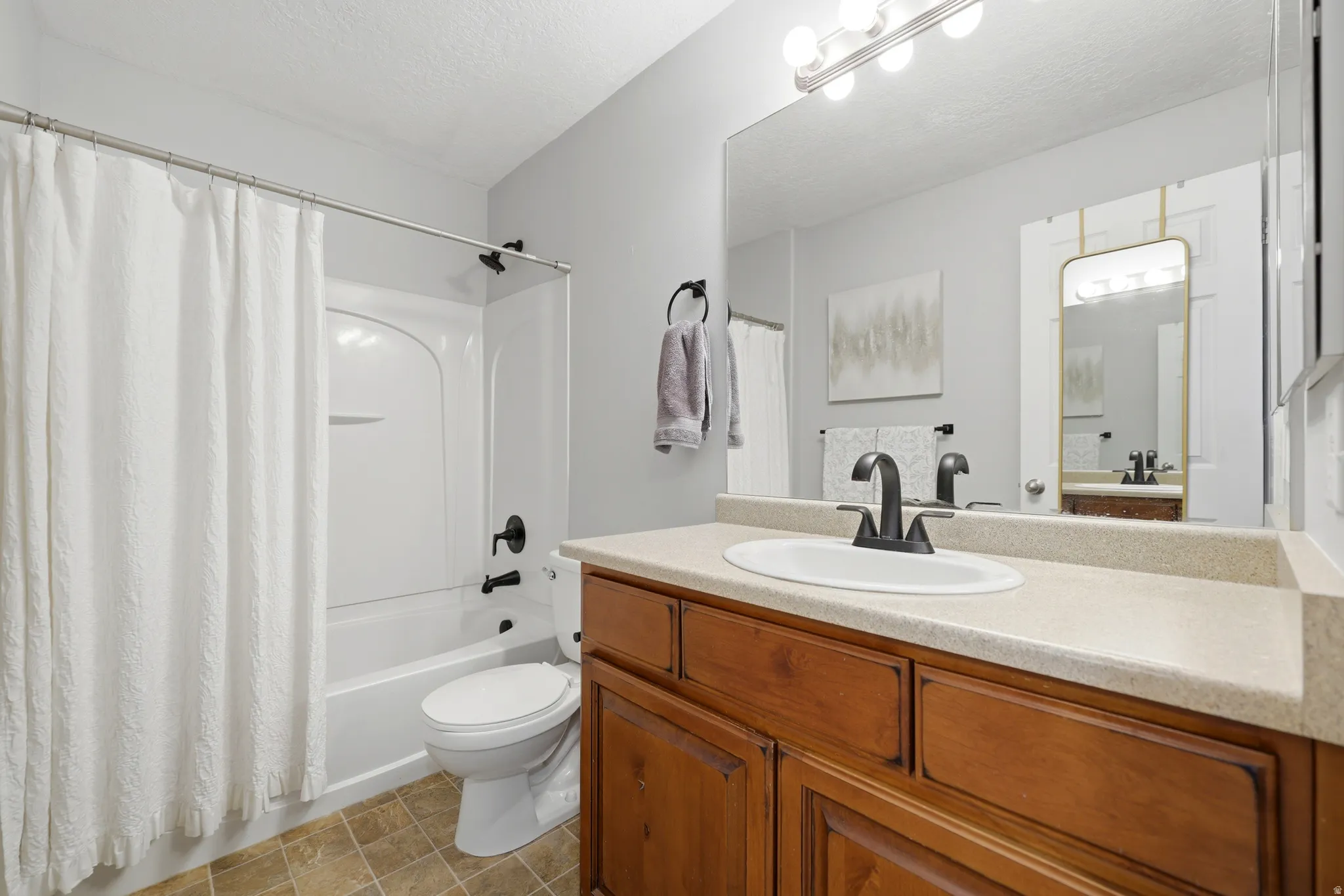Bathroom featuring a wood-finish vanity with a light-colored countertop and an integrated sink