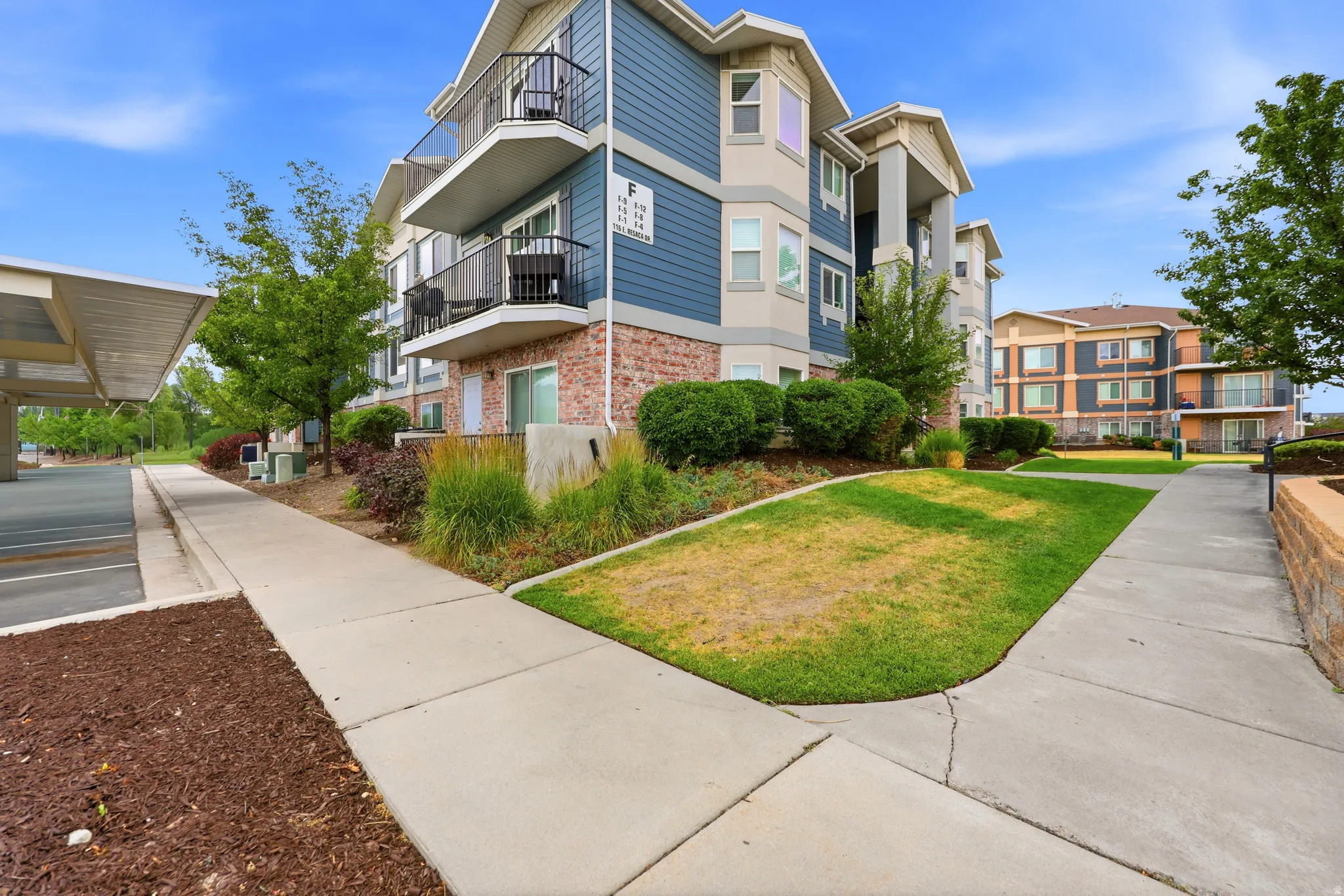 Multi-story building featuring brick and siding exterior, private balconies, and covered parking