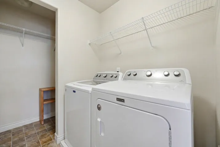 Dedicated laundry area featuring a washer and dryer, tile flooring, wire shelving, and an adjacent built-in wooden storage unit