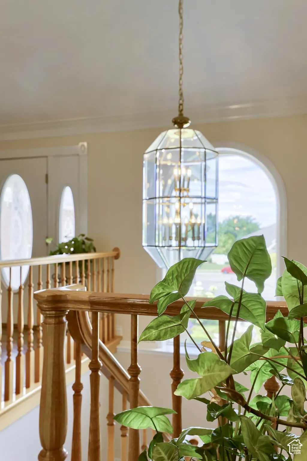 Foyer featuring a multi-tiered glass and brass chandelier, curved wooden banister, and an arched window