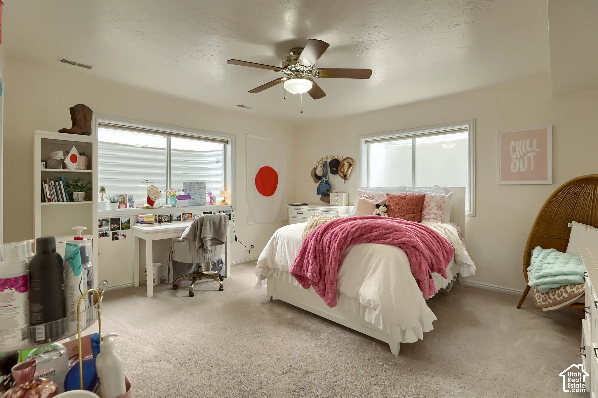 Carpeted room featuring a ceiling fan, dual windows, and built-in shelving