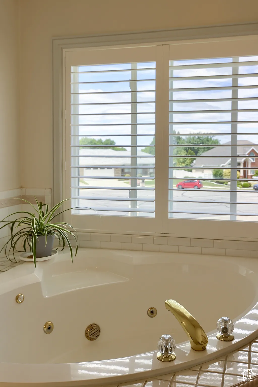 Built-in soaking tub with gold-tone fixtures and clear acrylic handles