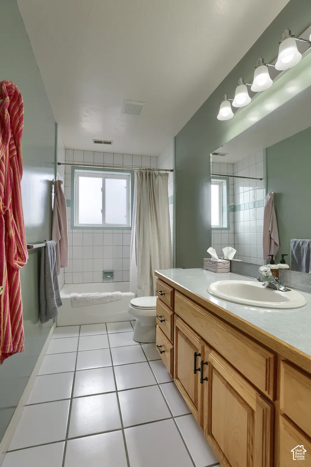 Bathroom featuring a wood-finish vanity with an integrated sink, a large mirror, and a four-bulb vanity light fixture