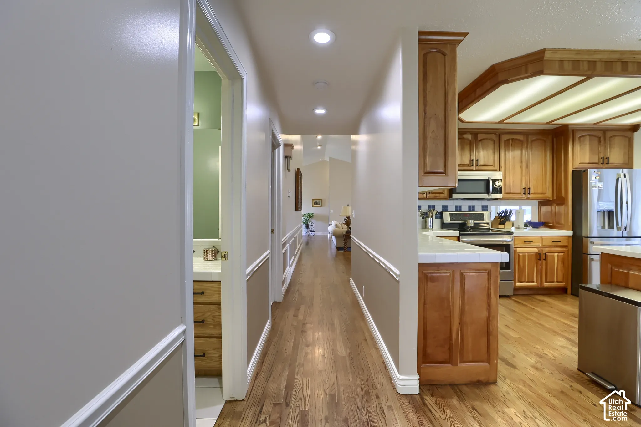 Hallway with wood-finish flooring, recessed lighting, and wainscoting detail
