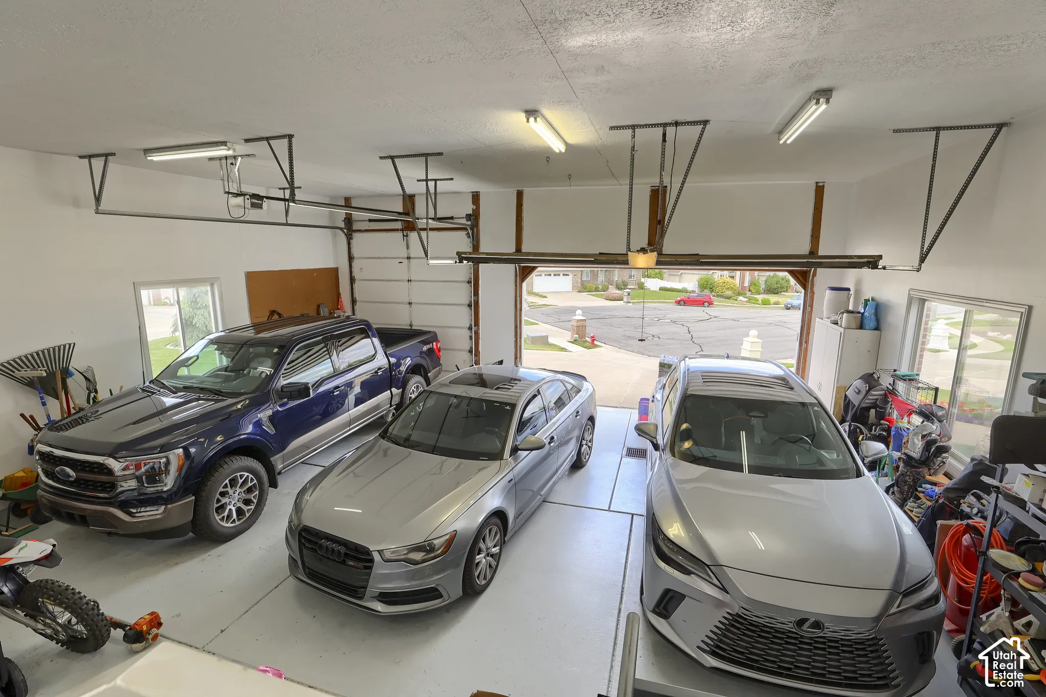 Spacious garage featuring white painted walls, exposed ceiling joists, and a light gray concrete floor
