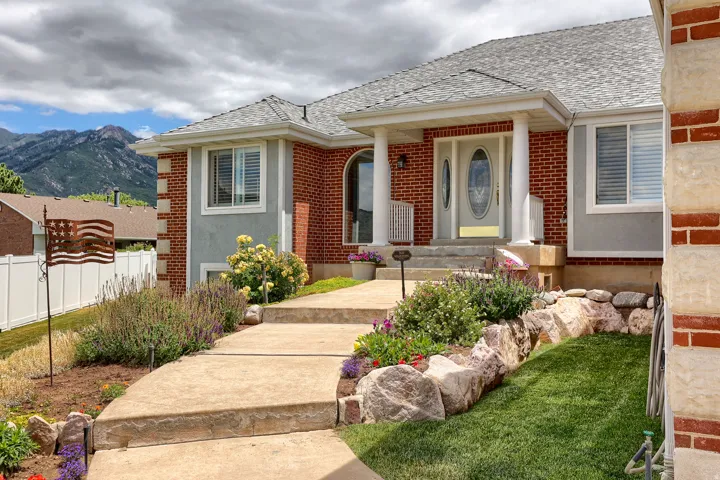 Brick and stucco exterior featuring a columned entryway, arched transom window, and a gray shingle roof