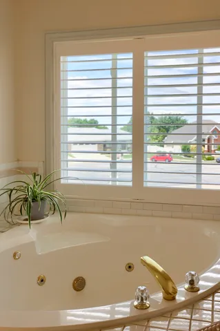 Built-in soaking tub with gold-tone fixtures and clear acrylic handles