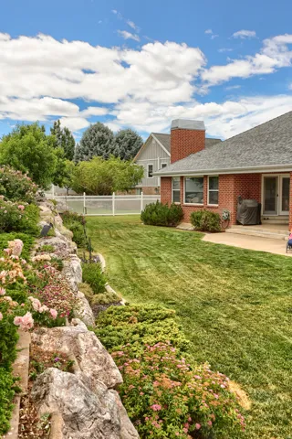 Spacious backyard featuring a manicured lawn, an expansive rock garden, and a white privacy fence
