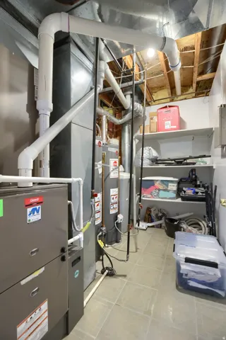 Dedicated utility room featuring mechanical systems, water heater, tile flooring, and integrated shelving