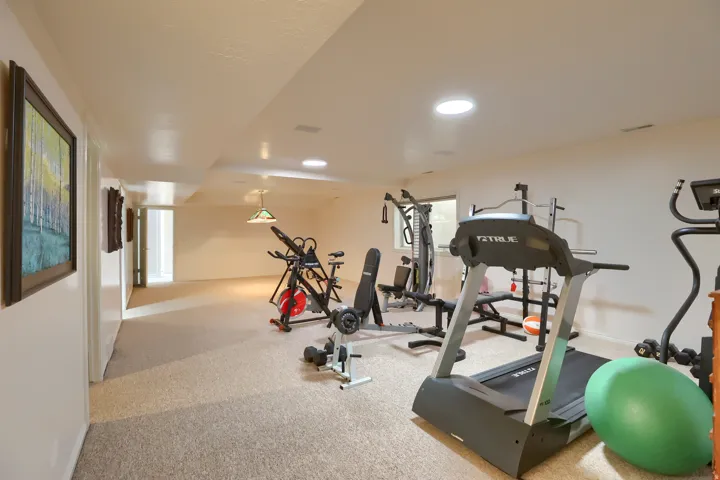 Expansive carpeted room featuring recessed lighting, a drop ceiling with integrated circular lights, and neutral-toned walls
