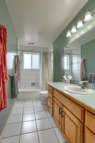 Bathroom featuring a wood-finish vanity with an integrated sink, a large mirror, and a four-bulb vanity light fixture