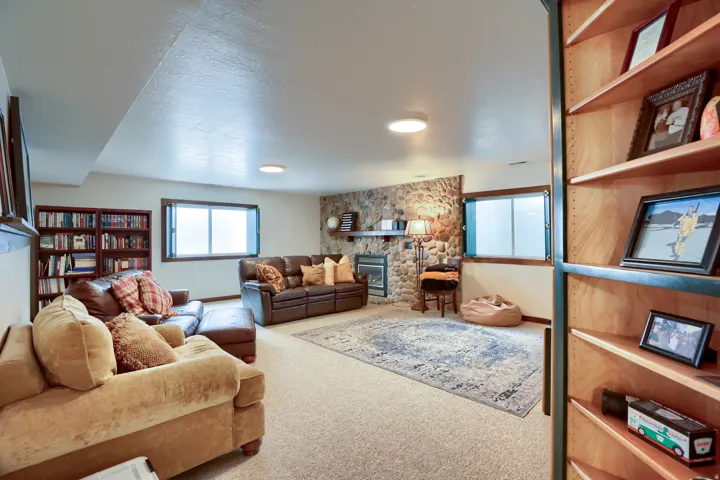Spacious lower level featuring a stone-clad fireplace, built-in shelving, two egress windows, and recessed lighting