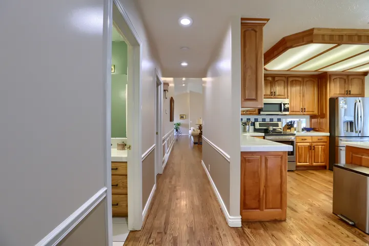 Hallway with wood-finish flooring, recessed lighting, and wainscoting detail