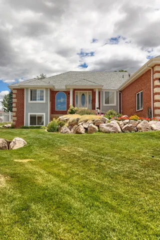 Brick and stucco exterior featuring a prominent arched window and a covered entry with columns