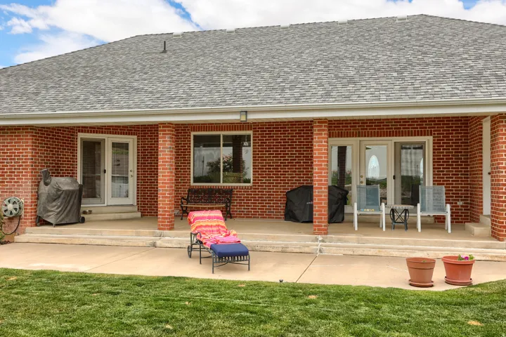 Covered patio featuring brick columns, red brick exterior, and a shingle roof