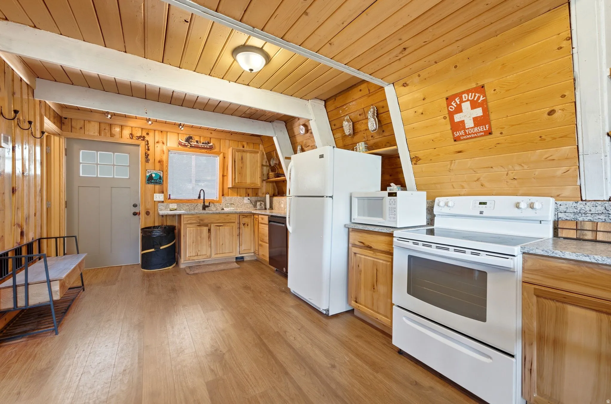 Kitchen featuring wood-finish flooring, wood cabinetry, stone-finish countertops, and a full suite of white appliances including a refrigerator, range, and microwave