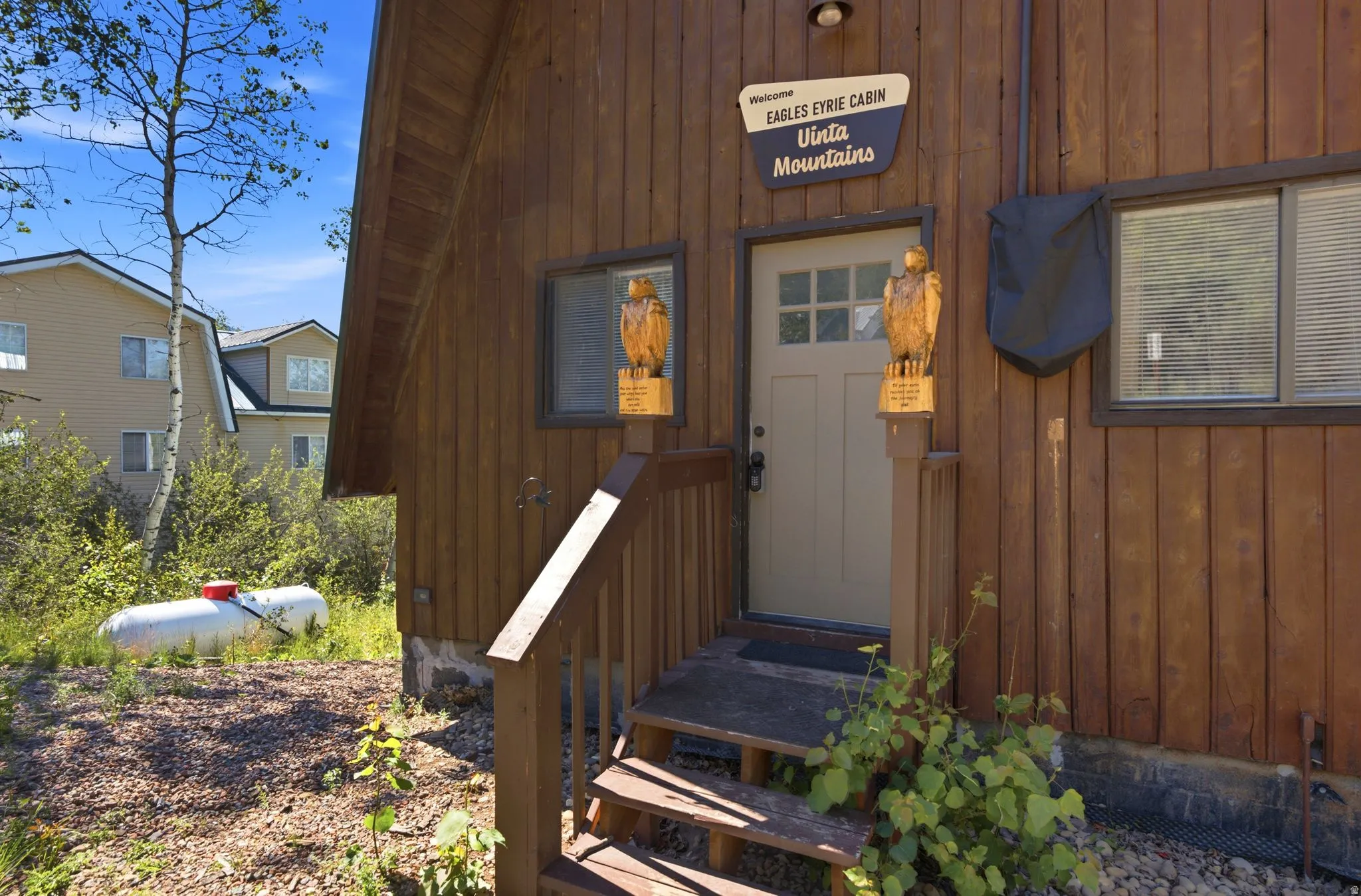 Wood-sided exterior featuring an entryway with a light-colored door and multiple windowpanes