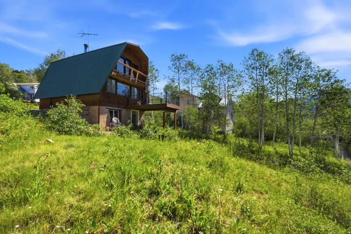 A-frame style residence with a dark green metal roof and wood siding