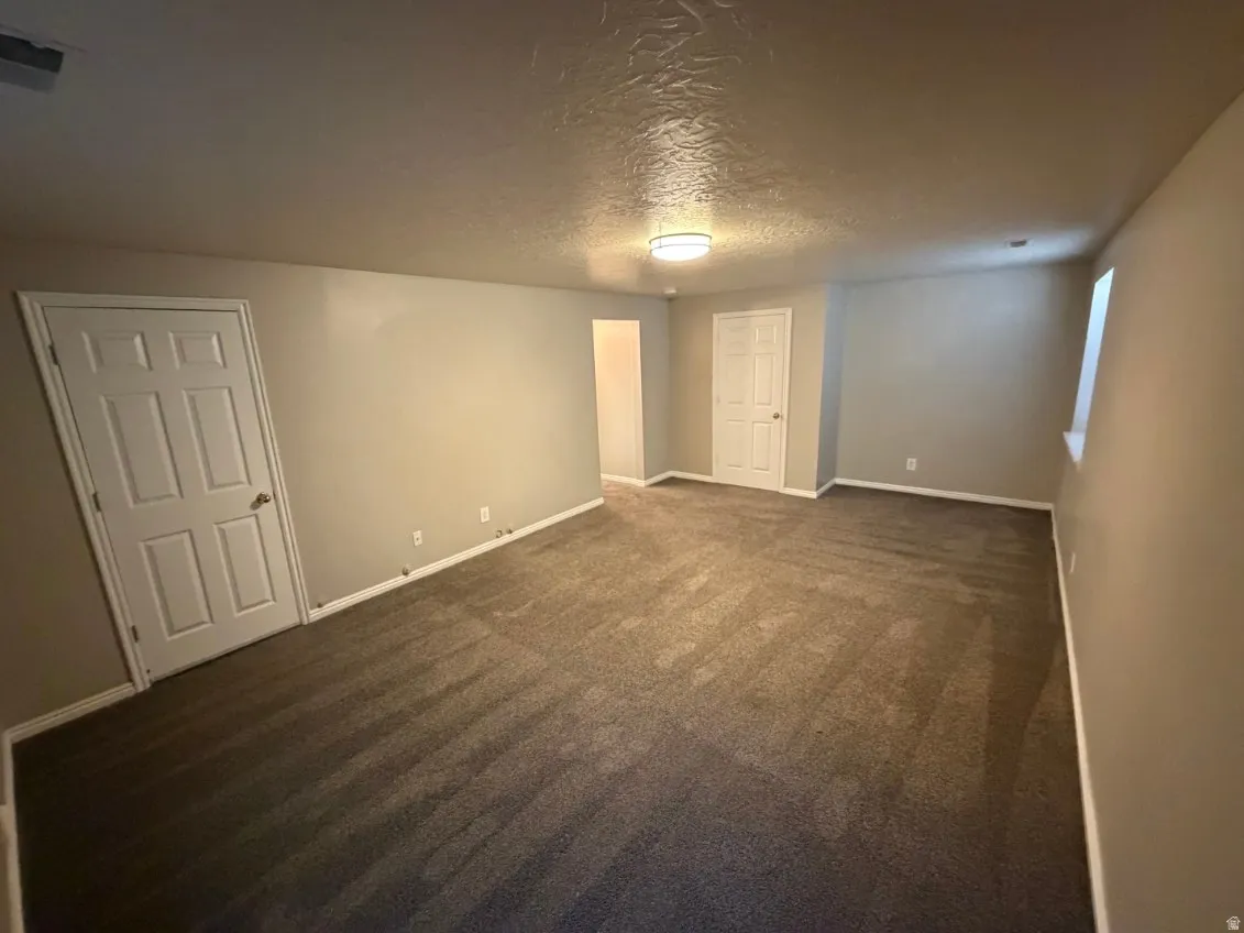 Carpeted room featuring neutral wall paint, white trim, and a flush-mount ceiling light fixture