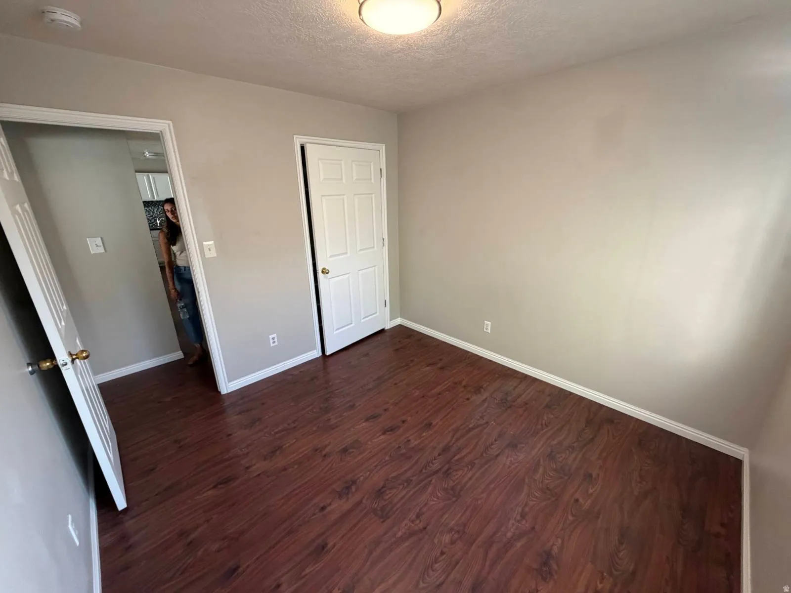 Room featuring wood-finish flooring, neutral wall paint, white trim, and a flush-mount ceiling light