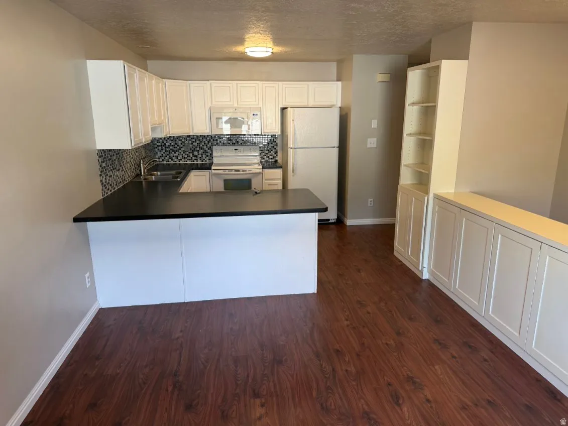 Kitchen with white cabinetry, dark countertops, and a mosaic tile backsplash