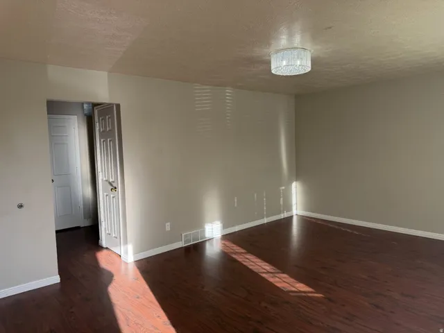 Spacious room featuring wood-finish flooring, neutral-toned walls, and white baseboards