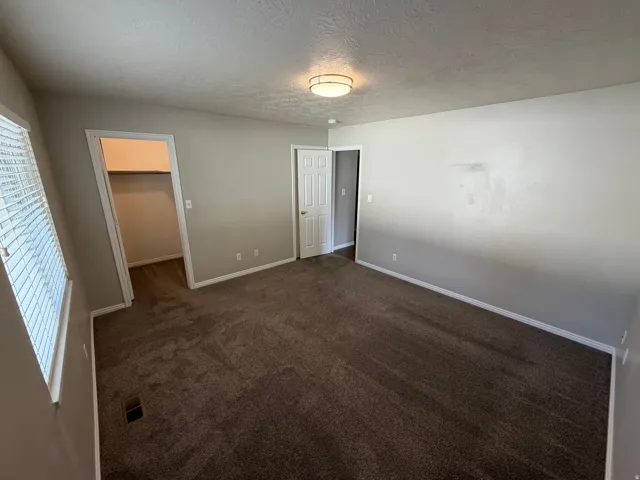 Spacious interior room featuring neutral wall tones and dark carpeting