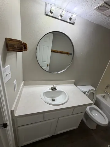 Bathroom vanity featuring a white oval sink, light-toned countertop, and white cabinetry