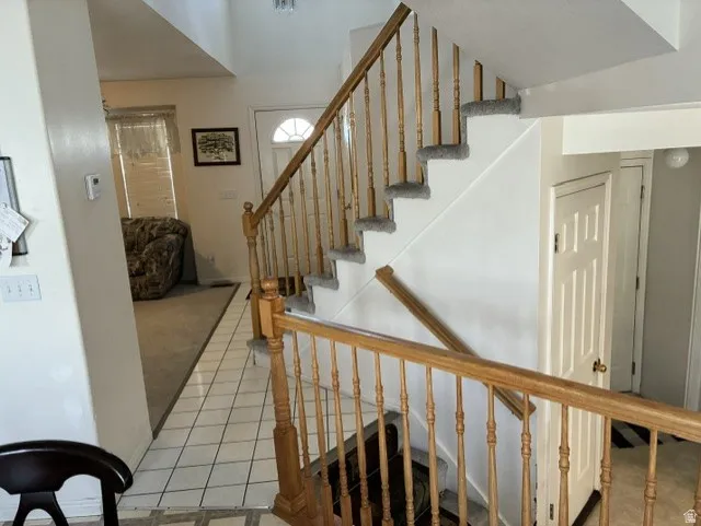Two-story entryway featuring a wood-finish staircase with carpeted treads