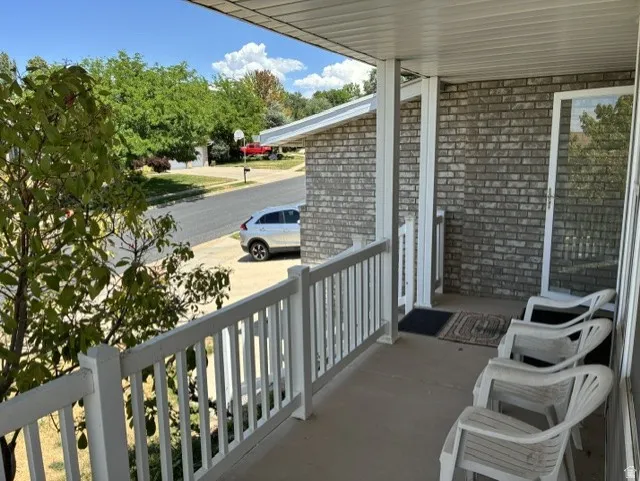 Covered porch with white railings and gray brick siding