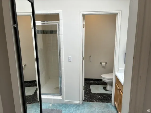 Bathroom featuring a walk-in shower with glass enclosure, white tile surround, and a black accent tile band