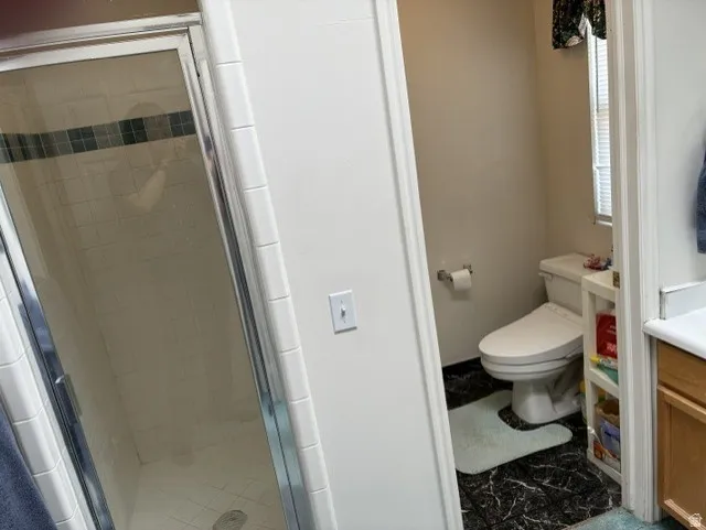 Walk-in shower with clear glass enclosure and subway tile surround, featuring a decorative tile accent band