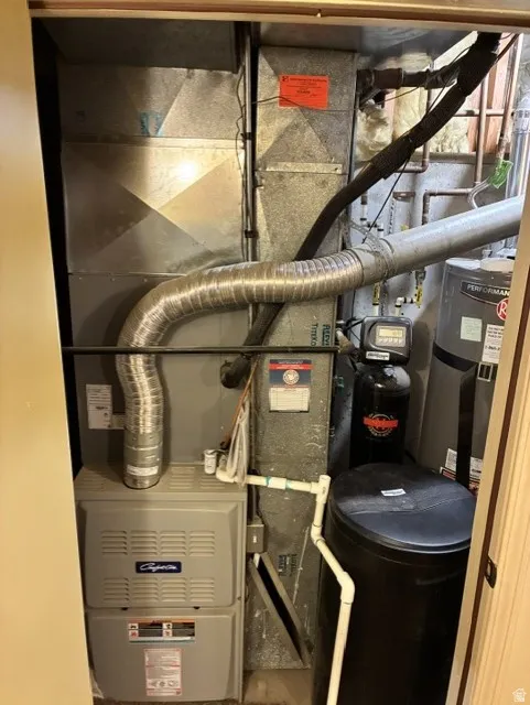 Utility closet featuring a furnace, water heater, water softener, and extensive ductwork