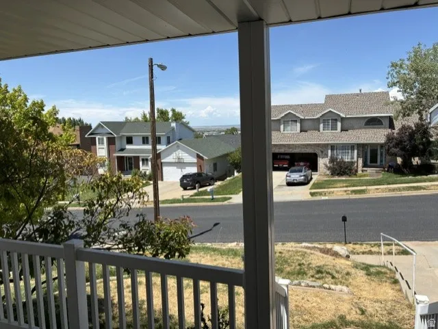 Front porch with white railings overlooking a residential street