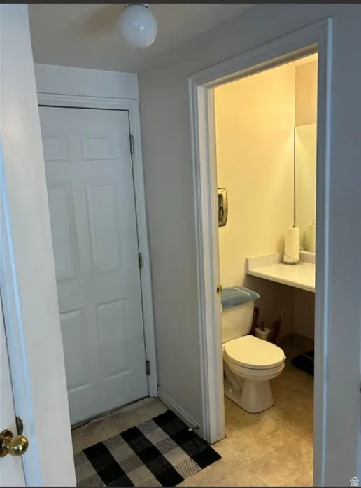 Interior doorway opening to a bathroom featuring a commode and a vanity with an integrated sink and mirror