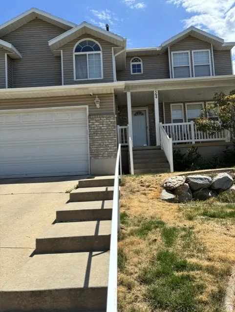 Split-level residence featuring a two-car garage and a covered porch entry