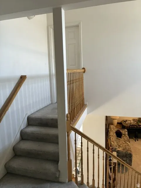 Carpeted staircase with wood-finish handrails and balusters