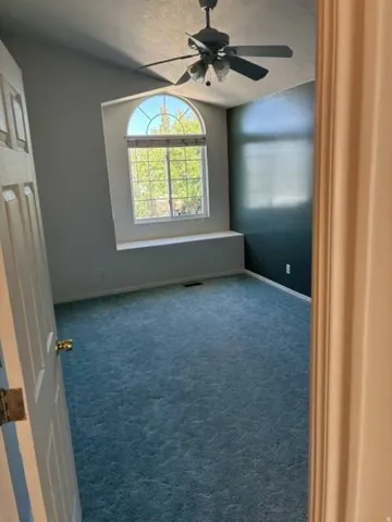 Arched window with integrated window seat, vaulted ceiling, and ceiling fan