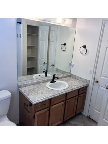 Vanity with an integrated sink, granite-style countertop, and wood-finish cabinetry